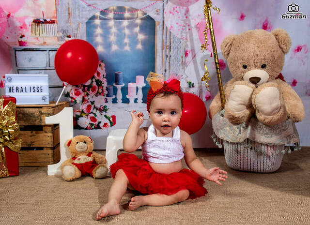 Bebé sentada entre globos y peluche — Producciones Guzmán SV